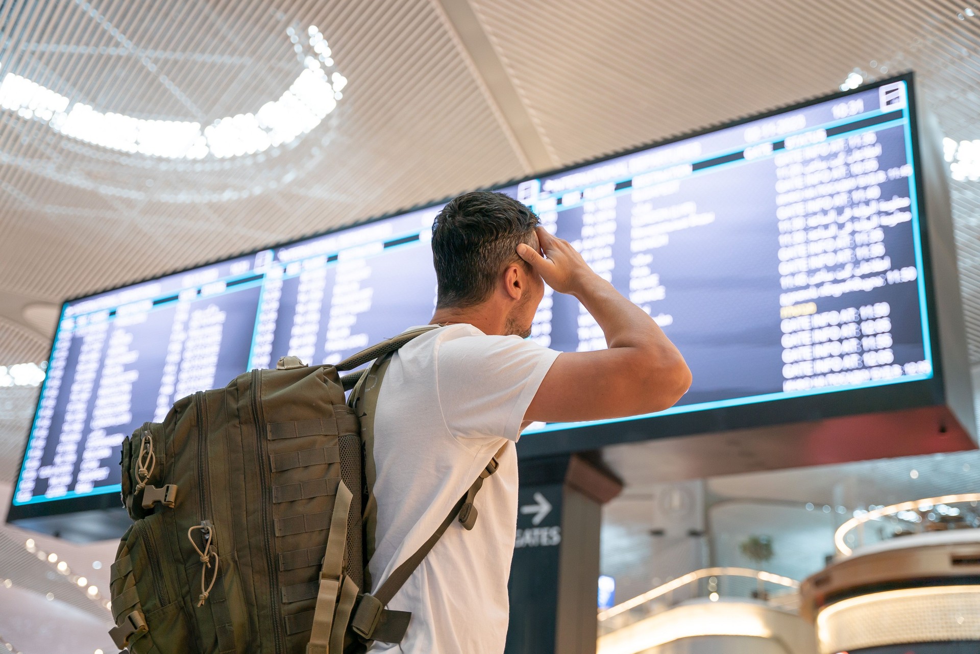 Man with backpack in airport near flight timetable