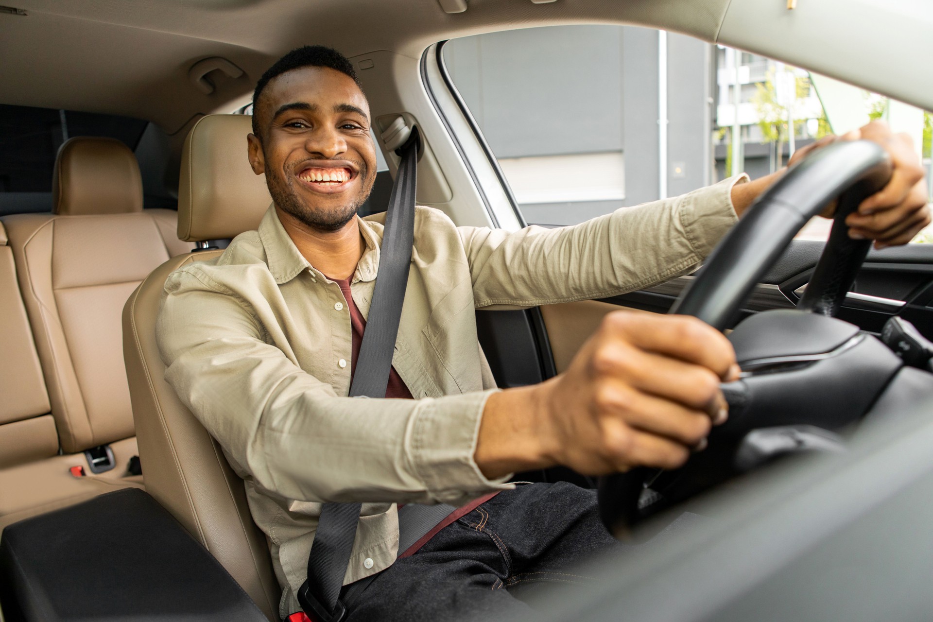African American driver with hands on steering wheel looking at camera